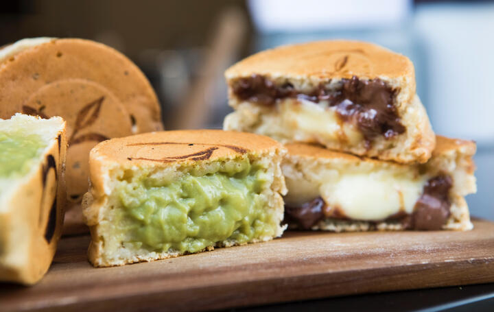 Wheel cakes cut in half, showing one with a matcha filling and another one with a chocolate and custard filling